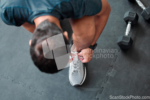 Image of Top view, man and tie shoes in gym to start workout, training or exercise for sports. Athlete, male and tying laces on sneakers to prepare for running, cardio or exercising for health or fitness.