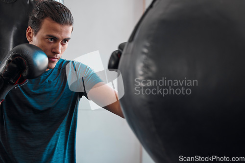 Image of Sports, boxing and man with punching bag in gym for training, exercise or workout. Boxer, athlete and male fighter punch for fight, competition or practice match, health and wellness for strength.