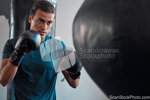Image of Sports, boxing and man with punching bag in gym for training, exercise or workout. Boxer, fitness athlete and serious fighter punch for fight, competition or practice, health or wellness for strength