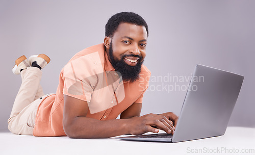 Image of Portrait, black man and laptop on studio floor to search social media, online shopping or subscription download. Happy male model typing on computer technology, internet blogging or elearning website