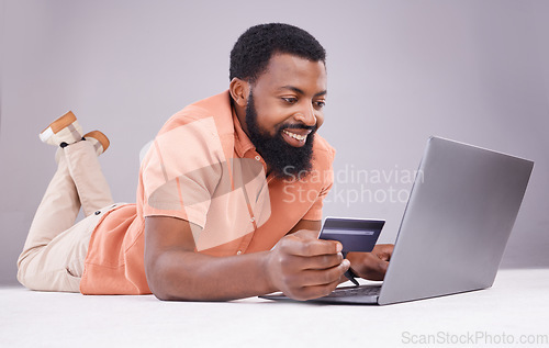 Image of Credit card, black man and smile on laptop in studio for online shopping, digital payment or money investment. Male model, ecommerce and computer sales for finance, fintech budget or internet banking