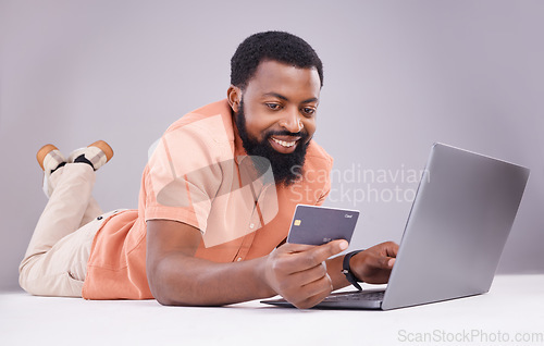 Image of Happy black man, credit card and laptop in studio for online shopping, digital financial payment and customer money. Male model, ecommerce and computer sales for finance, fintech and banking economy