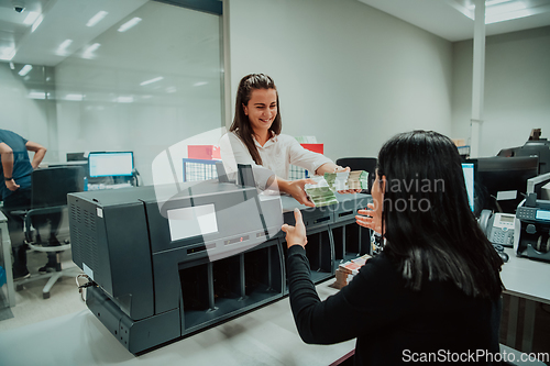 Image of Bank employees using money counting machine while sorting and counting paper banknotes inside bank vault. Large amounts of money in the bank