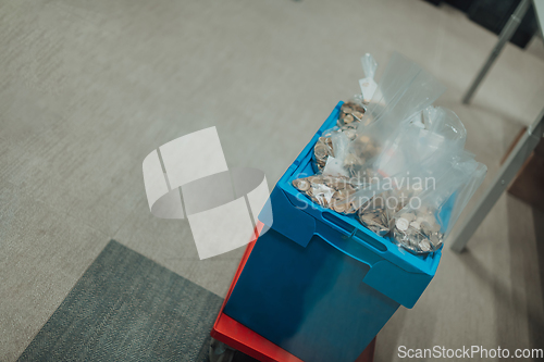 Image of Bank employees using money counting machine while sorting and counting small iron banknotes inside bank vault. Large amounts of money in the bank