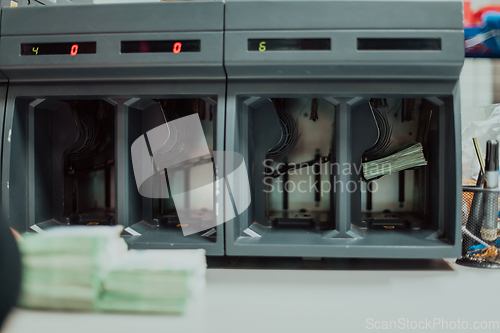 Image of Bank employees using money counting machine while sorting and counting paper banknotes inside bank vault. Large amounts of money in the bank