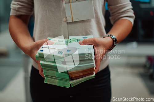 Image of Bank employees using money counting machine while sorting and counting paper banknotes inside bank vault. Large amounts of money in the bank