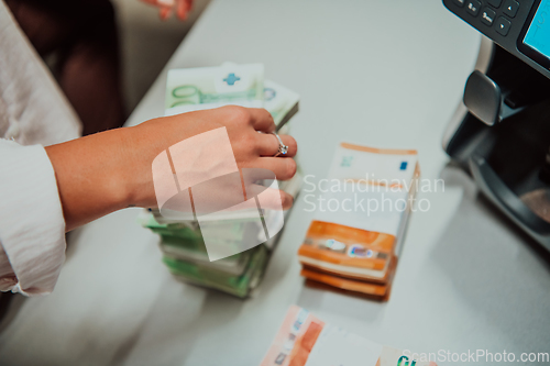 Image of Bank employees using money counting machine while sorting and counting paper banknotes inside bank vault. Large amounts of money in the bank