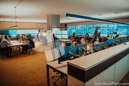 Image of Group of Security data center operators working in a CCTV monitoring room looking on multiple monitors.Officers Monitoring Multiple Screens for Suspicious Activities