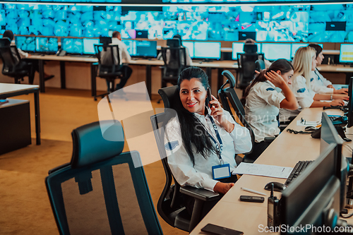 Image of Group of Security data center operators working in a CCTV monitoring room looking on multiple monitors.Officers Monitoring Multiple Screens for Suspicious Activities