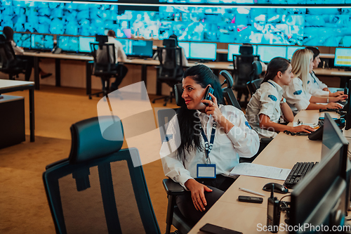 Image of Group of Security data center operators working in a CCTV monitoring room looking on multiple monitors.Officers Monitoring Multiple Screens for Suspicious Activities