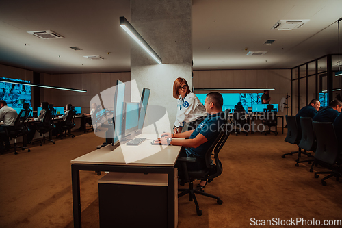 Image of Group of Security data center operators working in a CCTV monitoring room looking on multiple monitors Officers Monitoring Multiple Screens for Suspicious Activities Team working on the System Contr