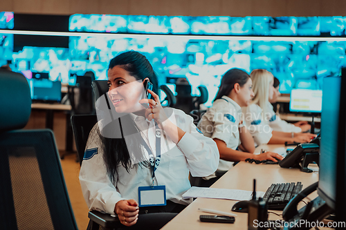 Image of Group of Security data center operators working in a CCTV monitoring room looking on multiple monitors.Officers Monitoring Multiple Screens for Suspicious Activities