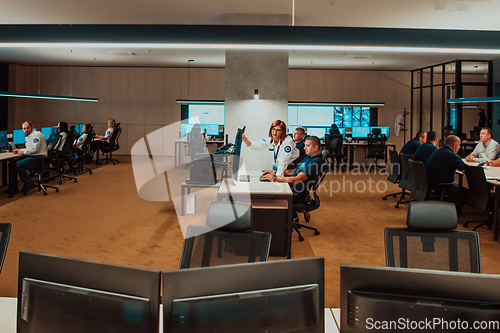 Image of Group of Security data center operators working in a CCTV monitoring room looking on multiple monitors Officers Monitoring Multiple Screens for Suspicious Activities Team working on the System Contr