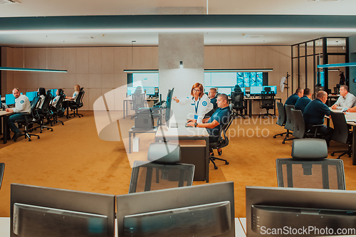 Image of Group of Security data center operators working in a CCTV monitoring room looking on multiple monitors Officers Monitoring Multiple Screens for Suspicious Activities Team working on the System Contr