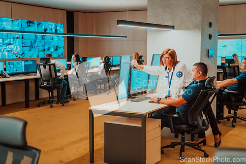 Image of Group of Security data center operators working in a CCTV monitoring room looking on multiple monitors Officers Monitoring Multiple Screens for Suspicious Activities Team working on the System Contr