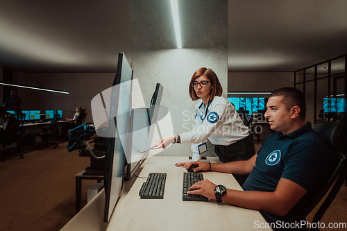 Image of Group of Security data center operators working in a CCTV monitoring room looking on multiple monitors Officers Monitoring Multiple Screens for Suspicious Activities Team working on the System Contr