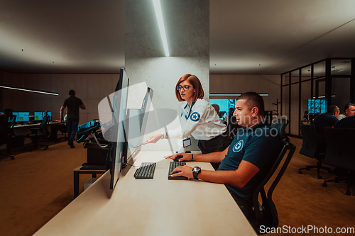 Image of Group of Security data center operators working in a CCTV monitoring room looking on multiple monitors Officers Monitoring Multiple Screens for Suspicious Activities Team working on the System Contr