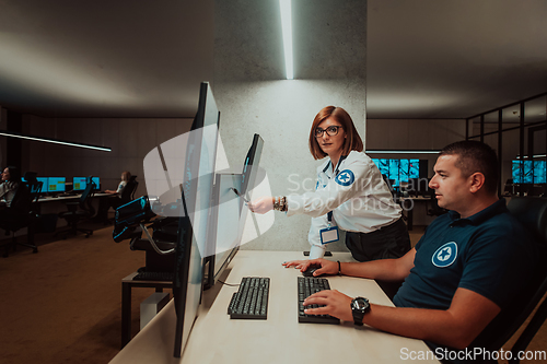 Image of Group of Security data center operators working in a CCTV monitoring room looking on multiple monitors Officers Monitoring Multiple Screens for Suspicious Activities Team working on the System Contr