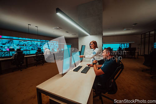 Image of Group of Security data center operators working in a CCTV monitoring room looking on multiple monitors Officers Monitoring Multiple Screens for Suspicious Activities Team working on the System Contr