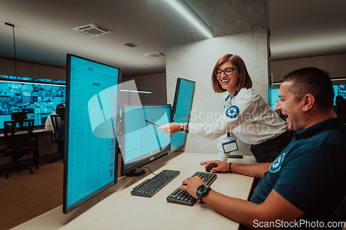 Image of Group of Security data center operators working in a CCTV monitoring room looking on multiple monitors Officers Monitoring Multiple Screens for Suspicious Activities Team working on the System Contr
