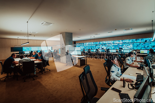 Image of Group of Security data center operators working in a CCTV monitoring room looking on multiple monitors.Officers Monitoring Multiple Screens for Suspicious Activities