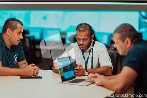 Image of Group of security guards sitting and having briefing In the system control room They're working in security data center surrounded by multiple Screens