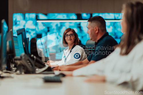 Image of Group of Security data center operators working in a CCTV monitoring room looking on multiple monitors.Officers Monitoring Multiple Screens for Suspicious Activities