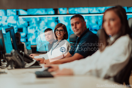 Image of Group of Security data center operators working in a CCTV monitoring room looking on multiple monitors.Officers Monitoring Multiple Screens for Suspicious Activities