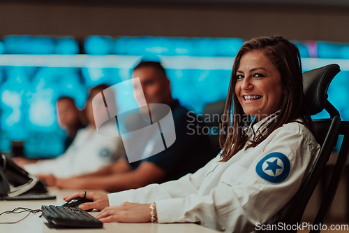 Image of Group of Security data center operators working in a CCTV monitoring room looking on multiple monitors.Officers Monitoring Multiple Screens for Suspicious Activities