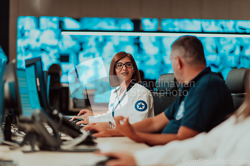 Image of Group of Security data center operators working in a CCTV monitoring room looking on multiple monitors.Officers Monitoring Multiple Screens for Suspicious Activities