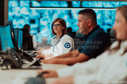 Image of Group of Security data center operators working in a CCTV monitoring room looking on multiple monitors.Officers Monitoring Multiple Screens for Suspicious Activities