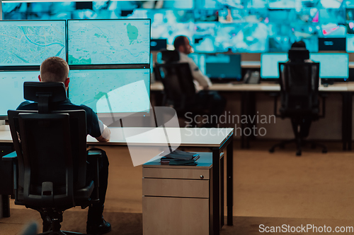 Image of Group of Security data center operators working in a CCTV monitoring room looking on multiple monitors.Officers Monitoring Multiple Screens for Suspicious Activities