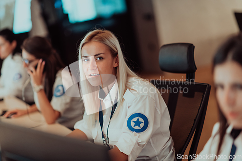 Image of Group of Security data center operators working in a CCTV monitoring room looking on multiple monitors.Officers Monitoring Multiple Screens for Suspicious Activities