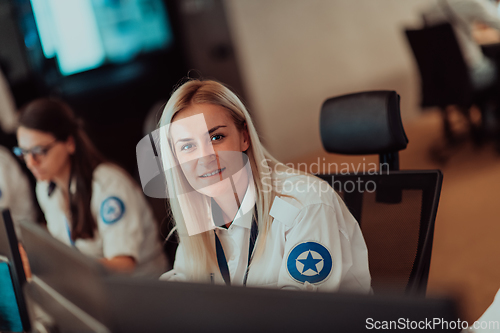 Image of Group of Security data center operators working in a CCTV monitoring room looking on multiple monitors.Officers Monitoring Multiple Screens for Suspicious Activities