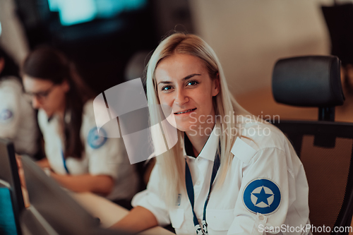 Image of Group of Security data center operators working in a CCTV monitoring room looking on multiple monitors.Officers Monitoring Multiple Screens for Suspicious Activities