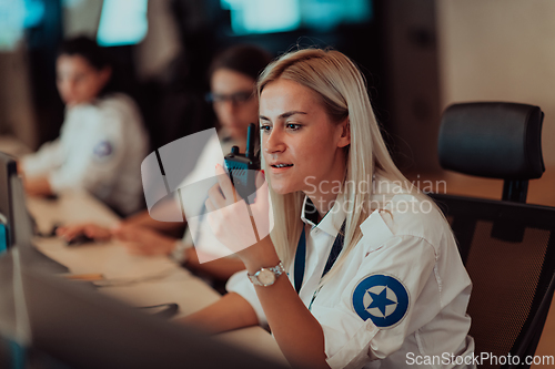 Image of Group of Security data center operators working in a CCTV monitoring room looking on multiple monitors.Officers Monitoring Multiple Screens for Suspicious Activities