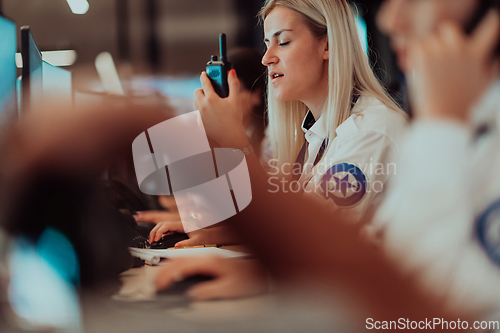 Image of Group of Security data center operators working in a CCTV monitoring room looking on multiple monitors.Officers Monitoring Multiple Screens for Suspicious Activities