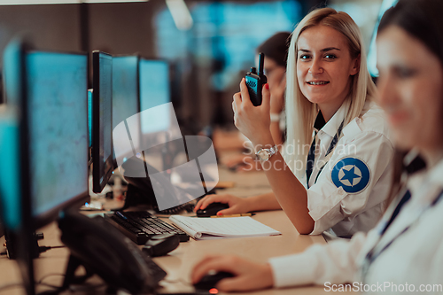 Image of Group of Security data center operators working in a CCTV monitoring room looking on multiple monitors.Officers Monitoring Multiple Screens for Suspicious Activities