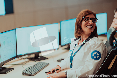 Image of Female security operator working in a data system control room offices Technical Operator Working at workstation with multiple displays, security guard working on multiple monitors