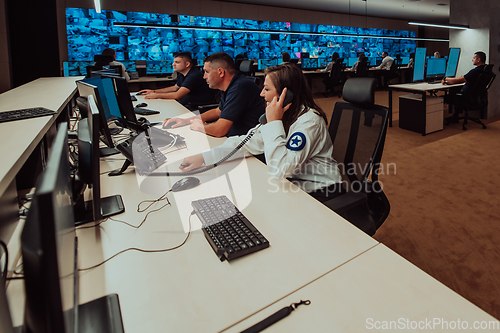 Image of Group of Security data center operators working in a CCTV monitoring room looking on multiple monitors.Officers Monitoring Multiple Screens for Suspicious Activities