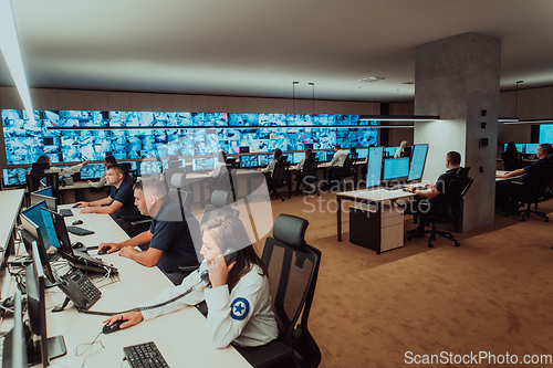 Image of Group of Security data center operators working in a CCTV monitoring room looking on multiple monitors.Officers Monitoring Multiple Screens for Suspicious Activities