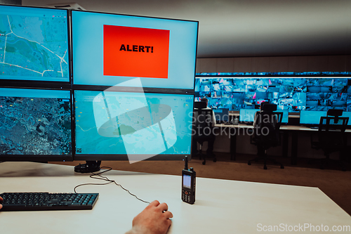 Image of Group of Security data center operators working in a CCTV monitoring room looking on multiple monitors.Officers Monitoring Multiple Screens for Suspicious Activities