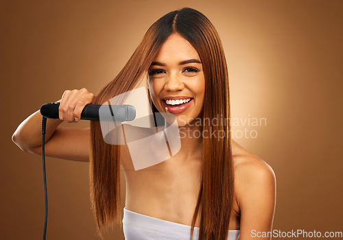 Image of Hair care, portrait of woman with flat iron, smile and beauty for luxury salon treatment tool on brown background. Beauty, electric straightener and happy model with straight hairstyle in studio.