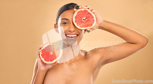 Image of Indian woman, grapefruit and beauty with face in portrait, natural cosmetics and organic treatment on studio background. Skincare, healthy glow and female smile with fruit product, skin and mockup