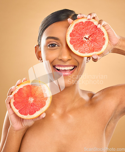 Image of Face smile, skincare and woman with grapefruit in studio isolated on a brown background. Portrait, natural cosmetics and happy Indian female model with citrus fruit for vitamin c, nutrition or beauty
