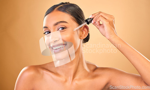 Image of Face portrait, skincare serum and woman in studio isolated on brown background. Dermatology, cosmetics and smile of Indian female model with hyaluronic acid, retinol or essential oil for healthy skin