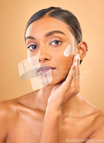 Image of Face portrait, skincare and woman with cream in studio isolated on a brown background. Dermatology, cosmetics or confident Indian female model with lotion, beauty creme or moisturizer for skin health