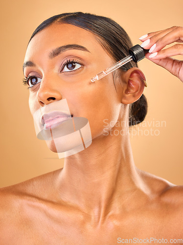 Image of Face, skincare serum and woman in studio isolated on a brown background. Dermatology cosmetics, thinking and Indian female model with hyaluronic acid, beauty retinol or essential oil for healthy skin