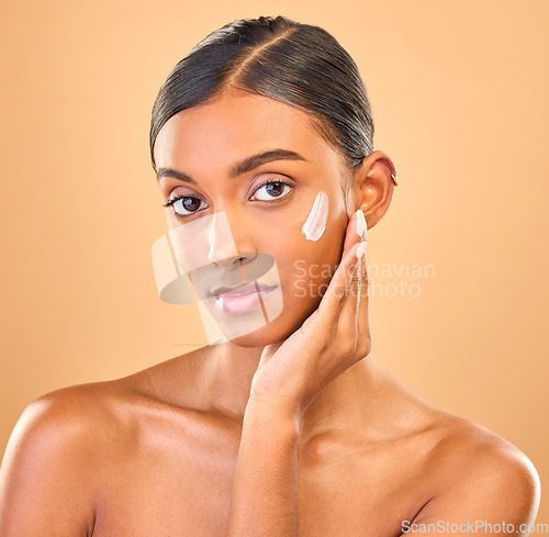 Image of Face portrait, skincare and woman with cream in studio isolated on a brown background. Dermatology, cosmetics or confident Indian female model with lotion, beauty creme or moisturizer for skin health