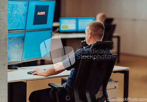 Image of Group of Security data center operators working in a CCTV monitoring room looking on multiple monitors.Officers Monitoring Multiple Screens for Suspicious Activities